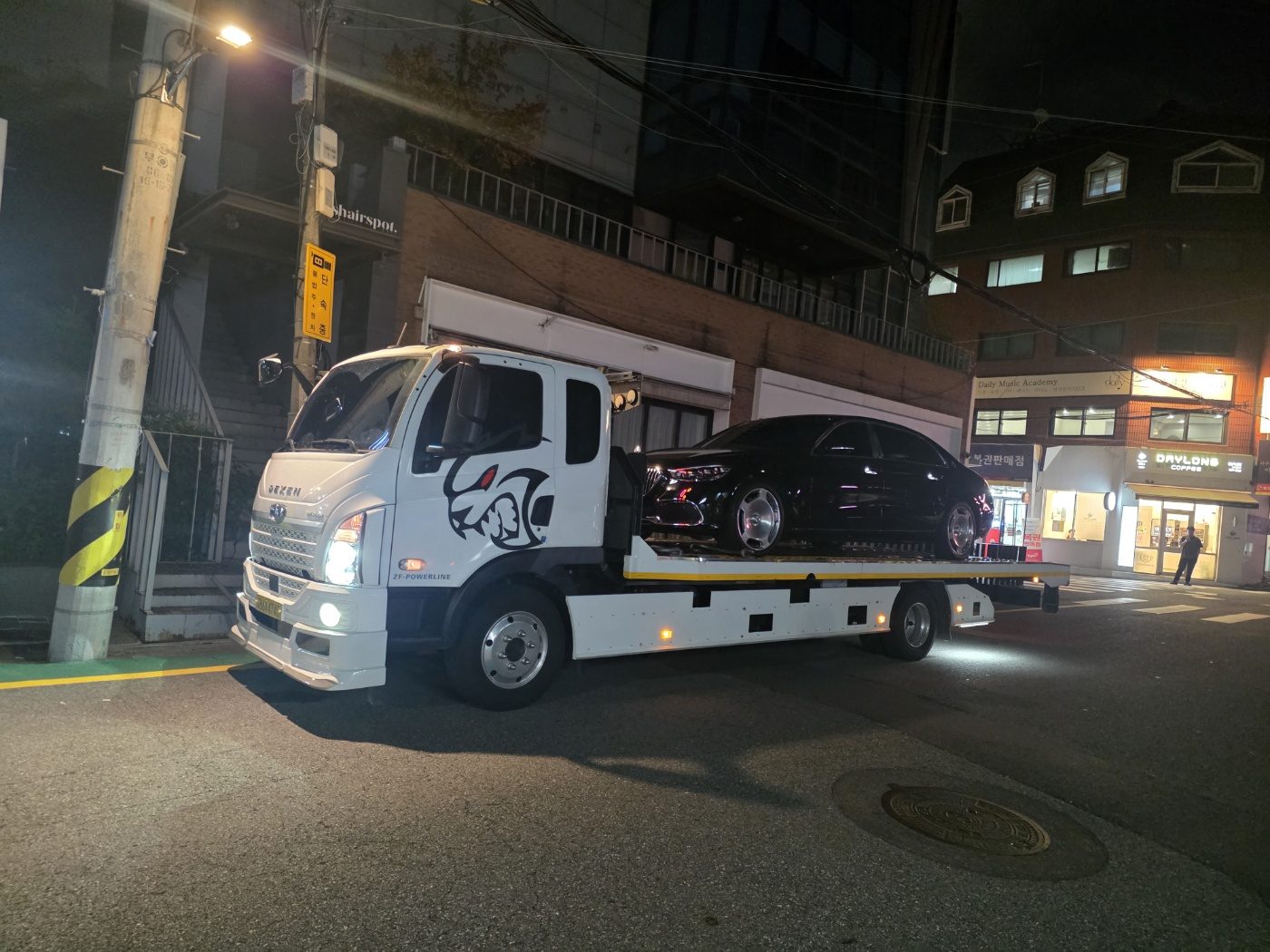 야간 도심에서 검은색 승용차를 적재함에 실은 모습
